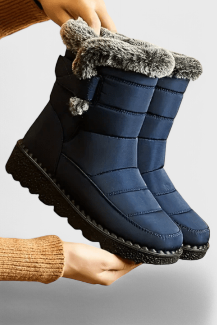Nessa wasserdichte Winterstiefel in Marineblau mit Kunstfellbesatz, Seitenansicht in Händen gehalten