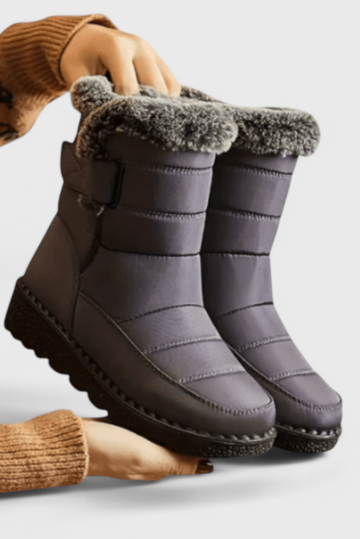Nessa wasserdichte Winterstiefel in Grau mit Kunstfellbesatz, Seitenansicht in Händen gehalten