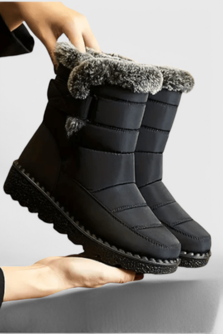 Nessa wasserdichte Winterstiefel in Schwarz mit Kunstfellbesatz, Seitenansicht in Händen gehalten