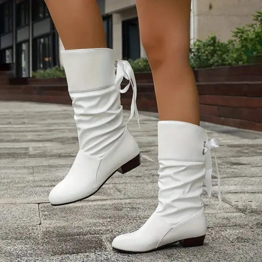 Weisse Stiefel mit Schleifenband, Nahaufnahme im Gehen