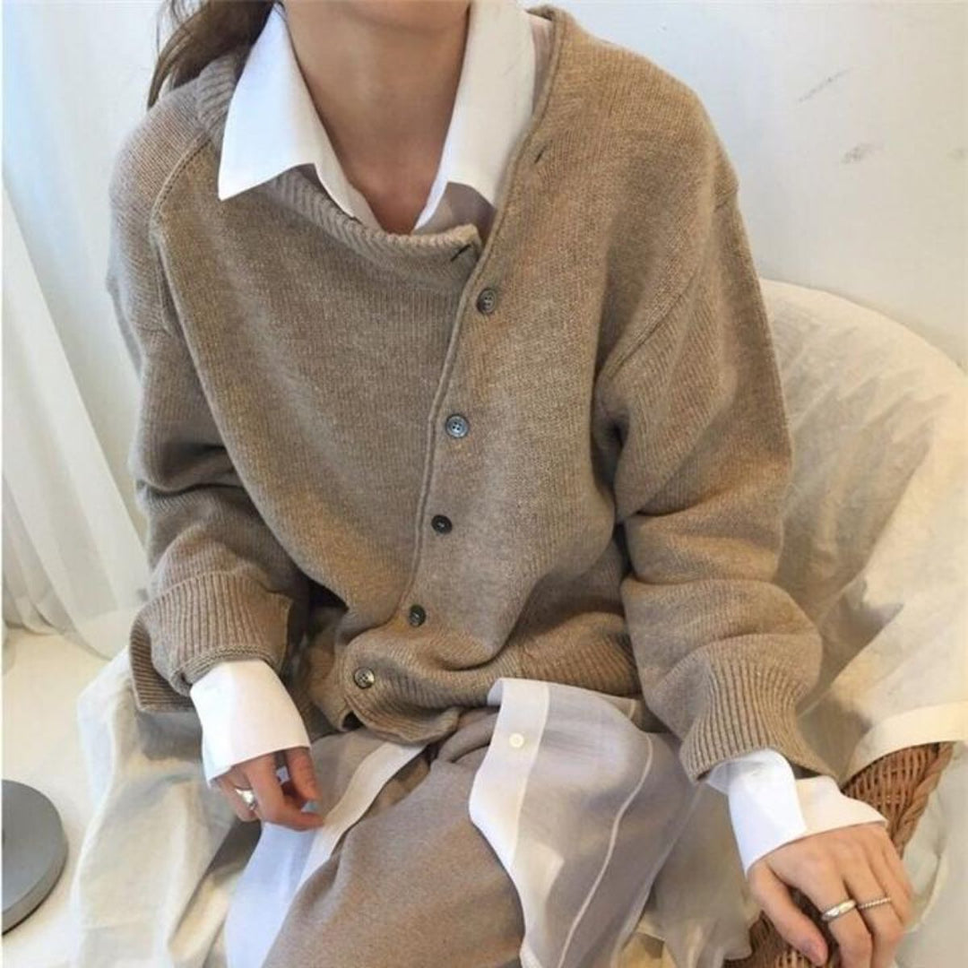 Solveig asymmetrischer Cardigan in Beige, sitzend mit verschränkten Händen